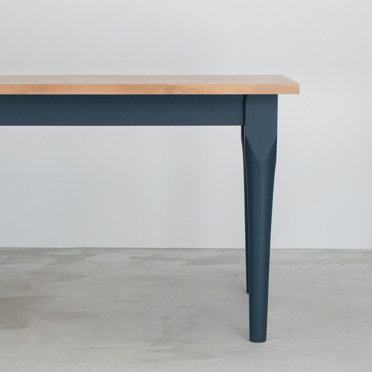 Design & Irony dining table with a plywood top and dark blue painted tapered legs