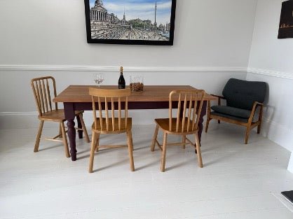 A wooden table with chairs in a white room. 