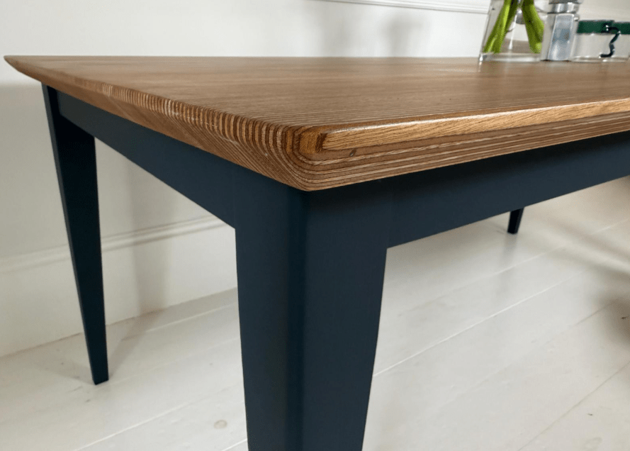 A close up of a edge-grain dining table in darker tones and black legs 